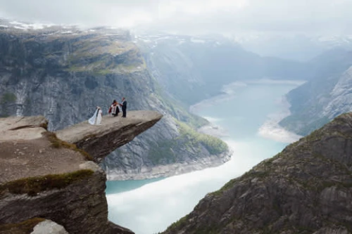 Un couple sur une falaise panoramique entourée de montagnes et d’une rivière, un cadre époustouflant pour une demande en mariage inoubliable.