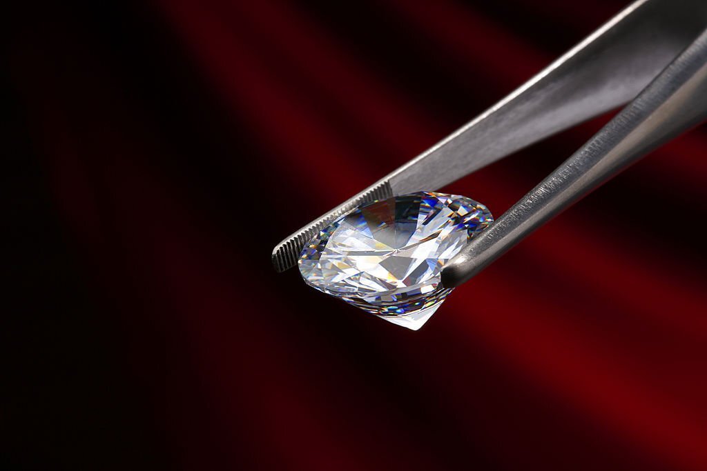 Diamant synthétique examiné par un gemmologue tenu par une pince